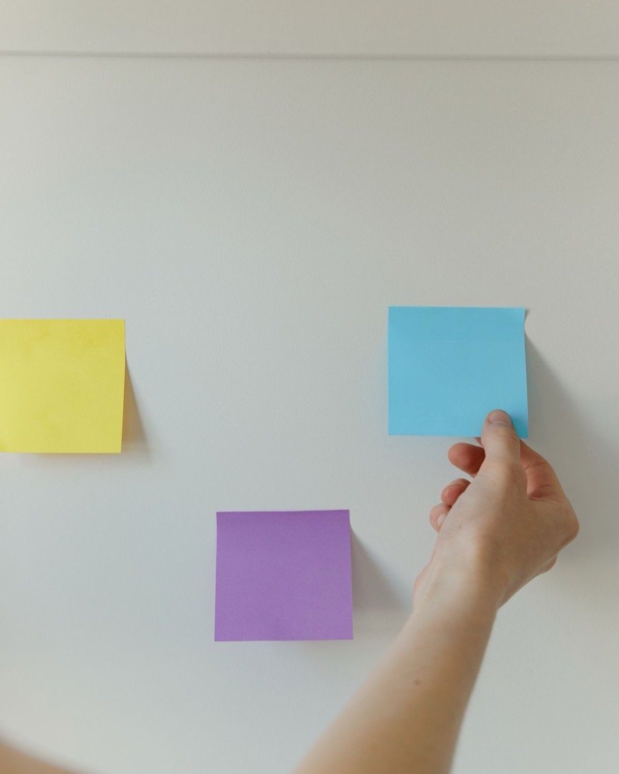 Une main qui compose un calendrier éditorial en pastilles de couleur sur un mur